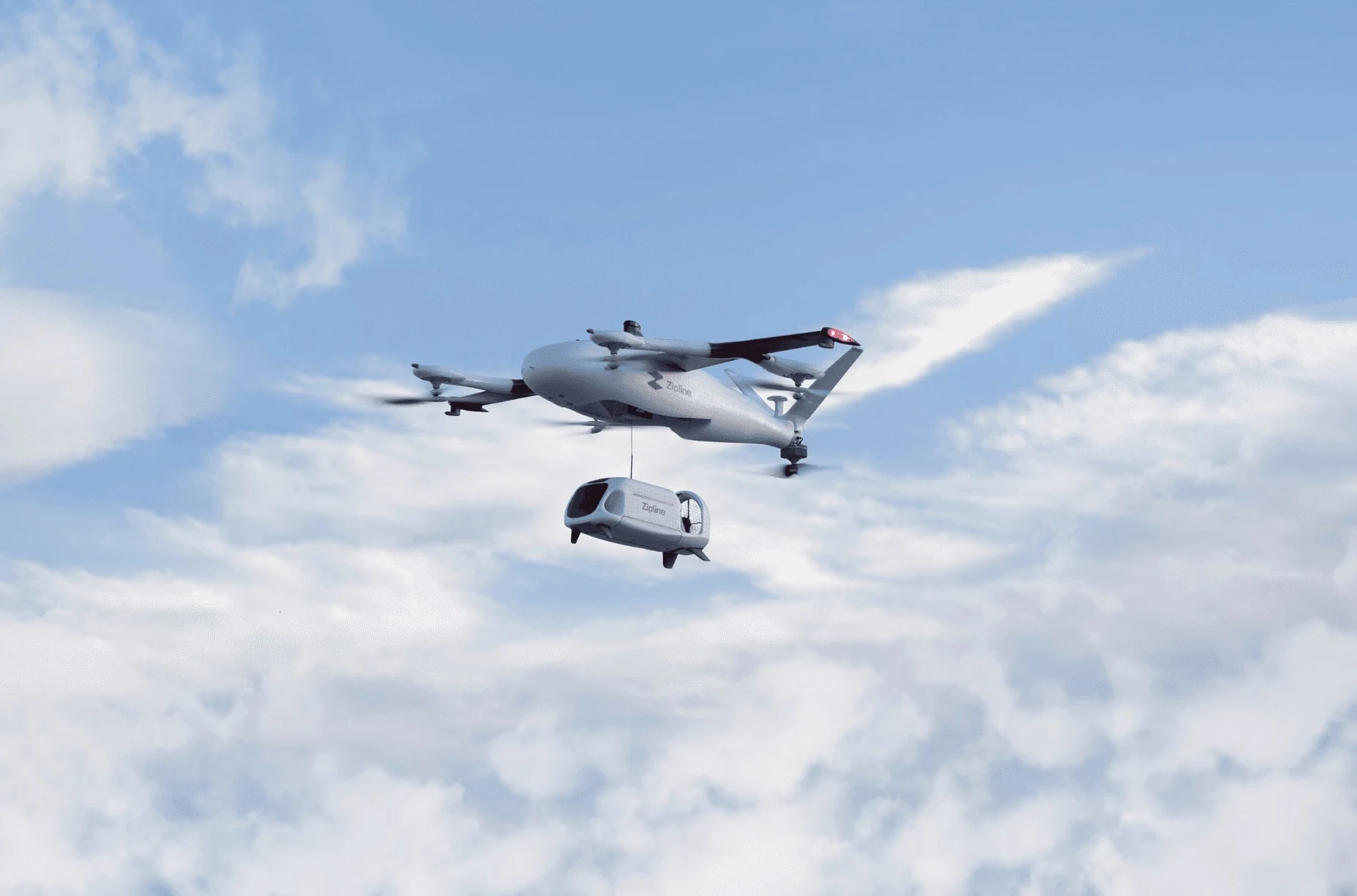 Zipline drone lowering a delivery pod against a blue sky
